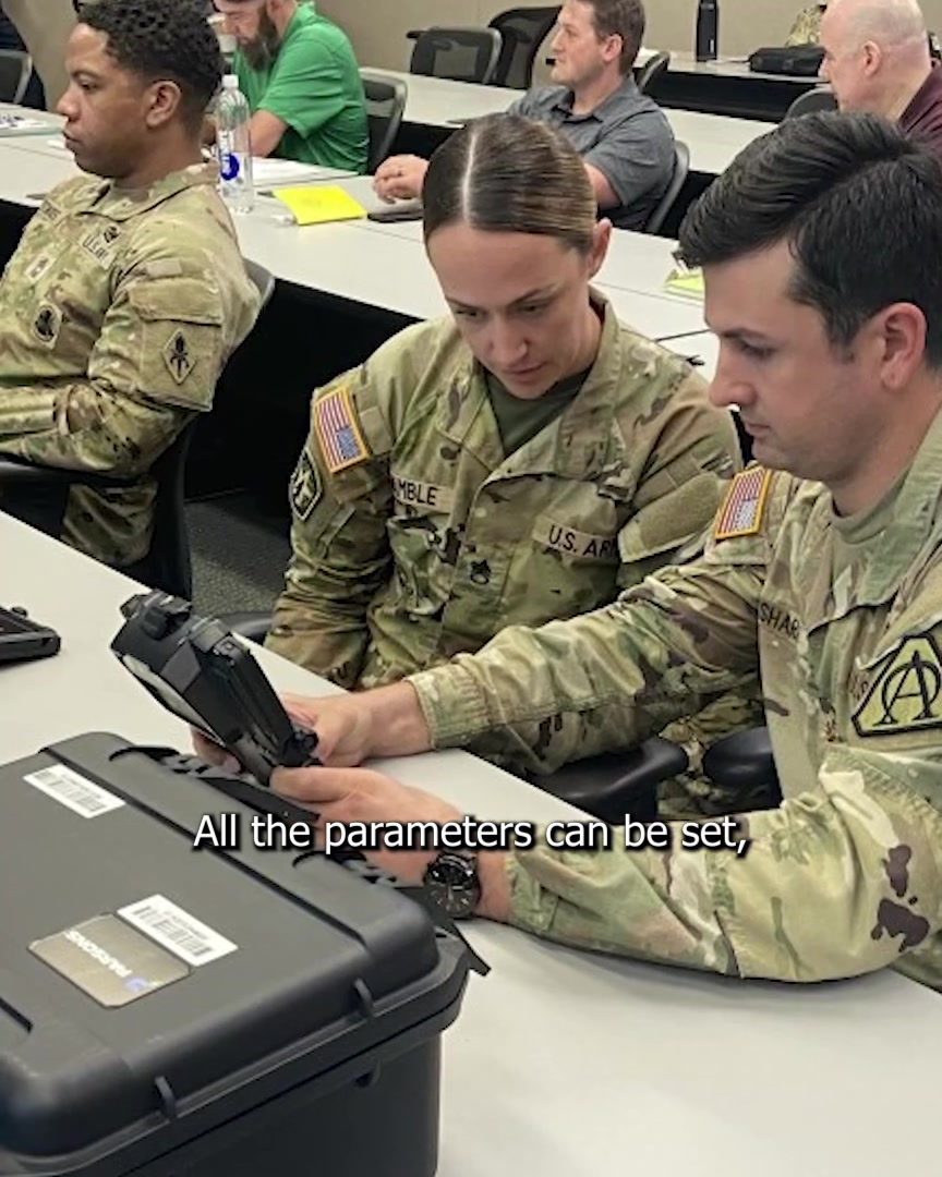 Military personnel reviewing biometric collection equipment during training